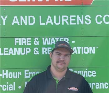 SERVPRO employee standing in front of a green SERVPRO truck