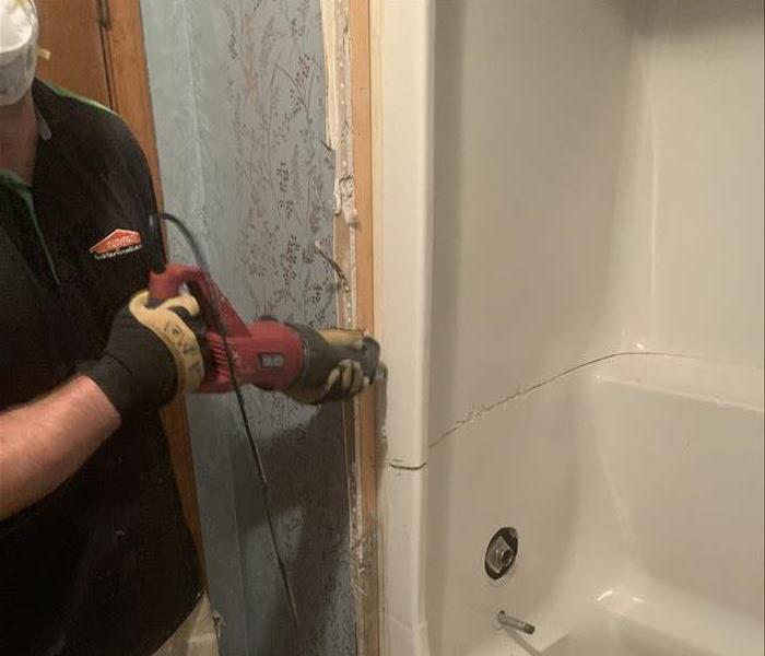 SERVPRO technician removing a shower from a home after severe water damage