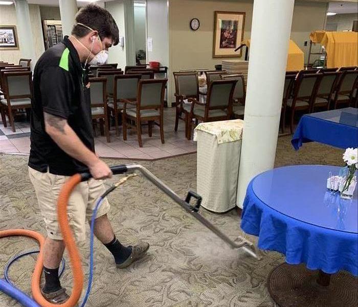 SERVPRO Technician cleaning the carpet in the dining hall of a Retirement Home.